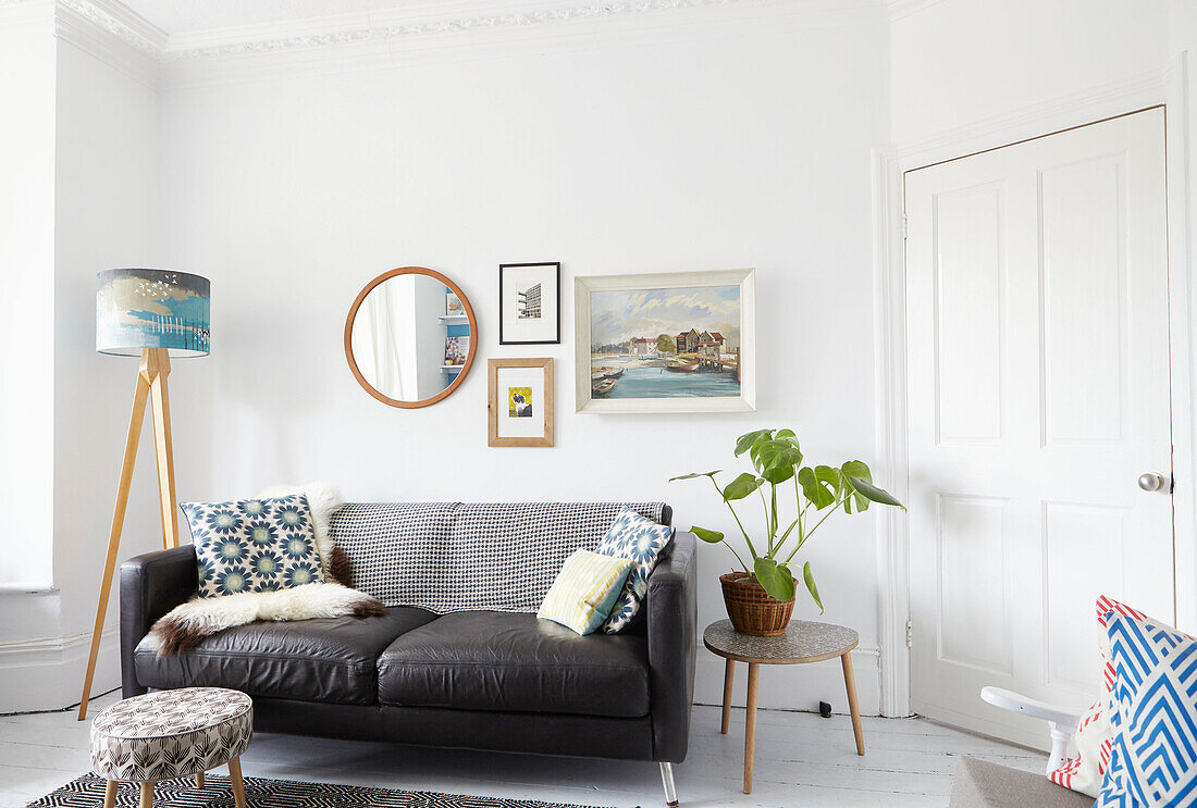 Spiegel und Kunstwerk über Zweisitzer-Sofa mit Lampe im Wohnzimmer in Sheffield Yorkshire UK