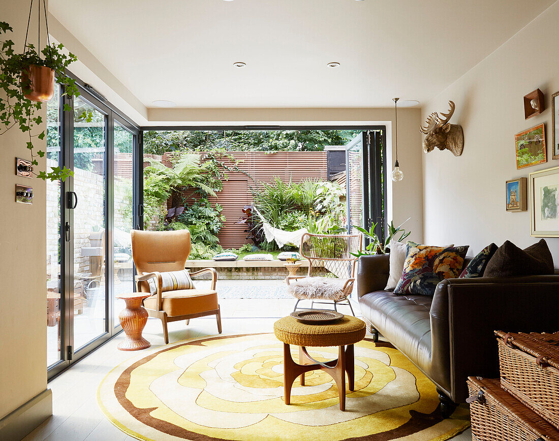 Braunes Ledersofa mit Ablagekörben im Wohnzimmer eines Stadthauses im Osten Londons, England UK