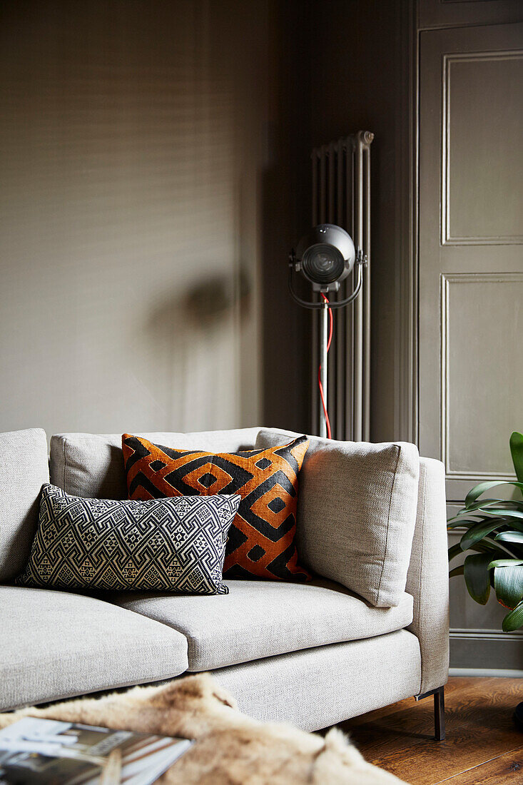 Gemusterte Kissen und Studioleuchte mit cremefarbenem Sofa in einem Stadthaus im Osten Londons England UK