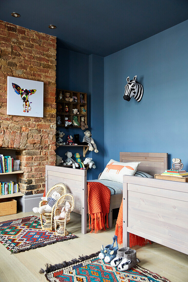 Soft toys and single bed with exposed brick wall in child's room  East London townhouse  England  UK