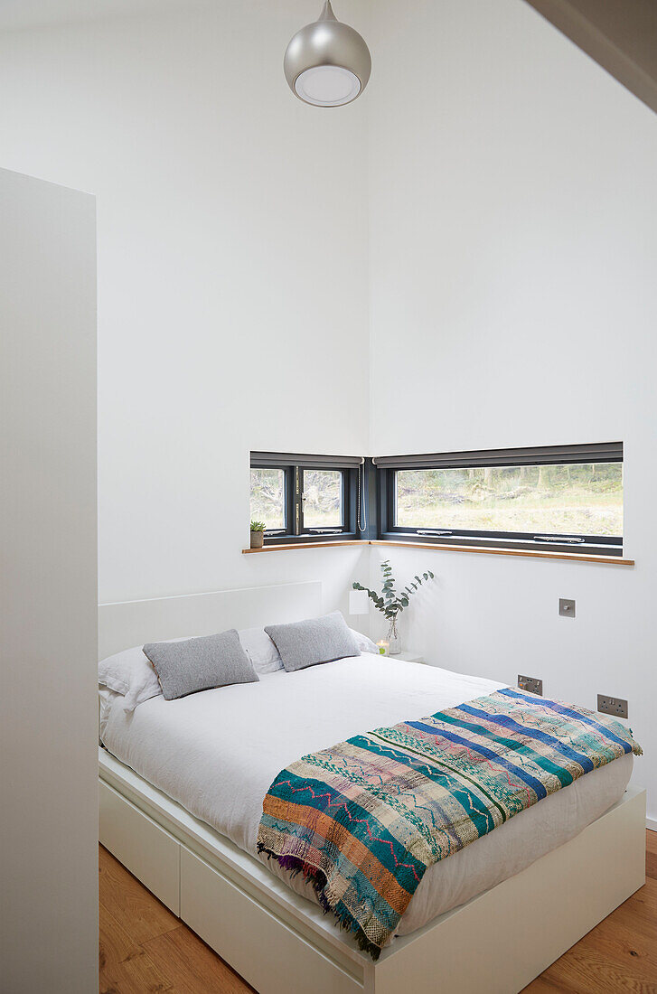 Gemusterte Decke auf einem Doppelbett in einem Neubau in Devon (UK)