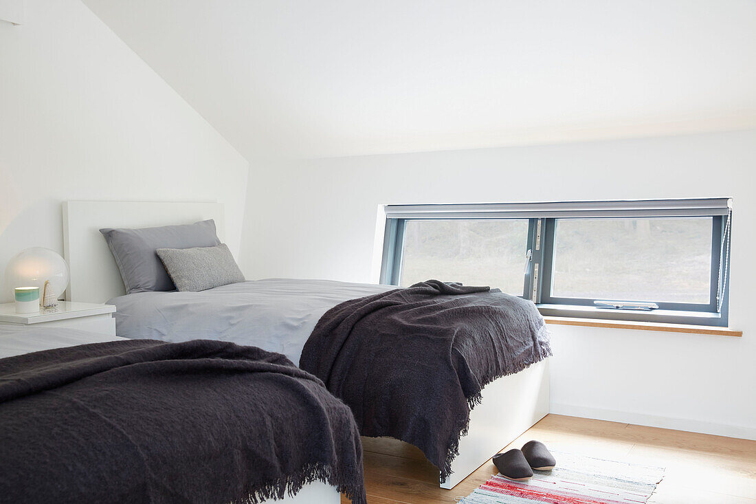 Braune Decken auf Einzelbetten am Fenster in einem Neubau in Devon UK