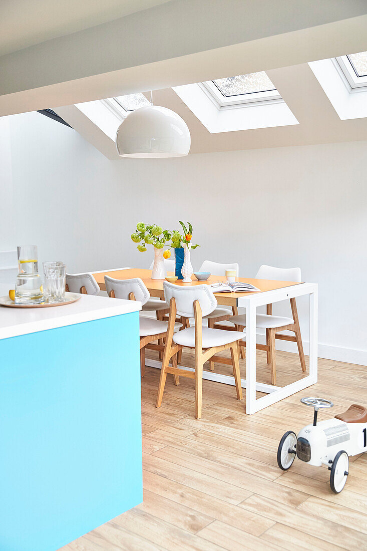 Tisch und Stühle unter Dachfenstern mit Spielzeugauto in modernisiertem Küchenanbau London UK