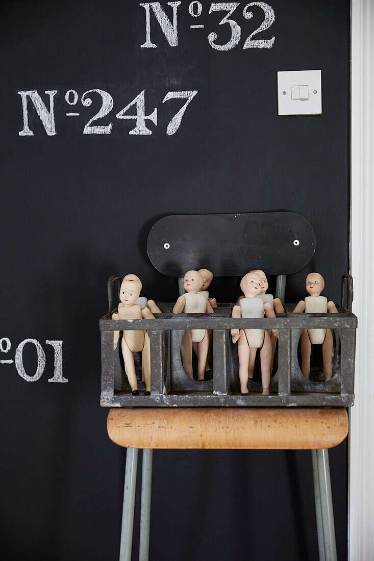 Puppen in einer Kiste auf einem alten Stuhl im Haus in Rochester, Kent UK
