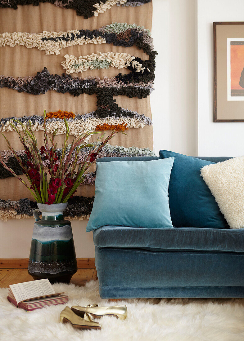 Blumenarrangement und Wandbehang mit tealfarbenem Sofa in London UK