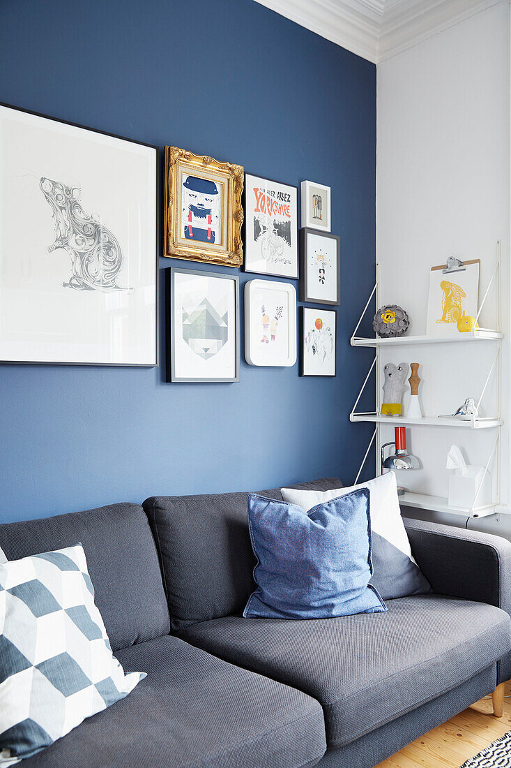 Gerahmte Kunstwerke und Regale mit grauem Sofa in einer modernisierten Wohnung in Preston, Lancashire, England UK