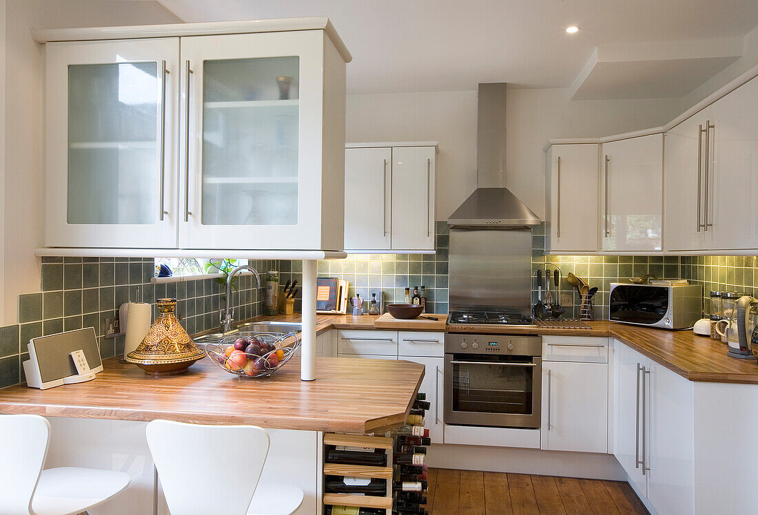 Frühstücksbar mit Weinregal in weißer Einbauküche in einem Haus in New Malden, Surrey, England, UK
