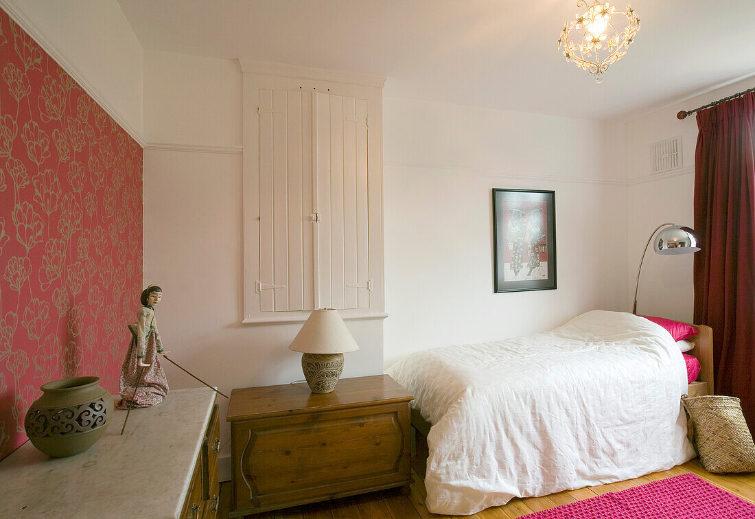 Single bed in room with built in storage cupboard and floral patterned feature wall in New Malden home, Surrey, England, UK