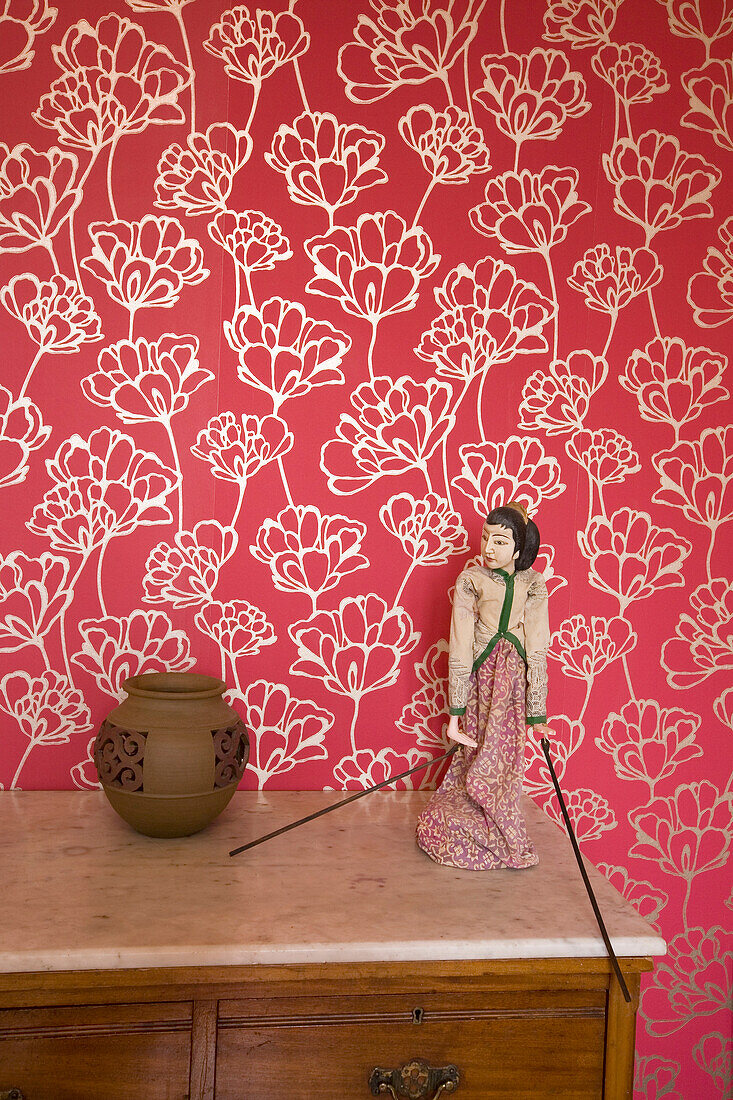 Red floral patterned oriental wallpaper and figurine in New Malden home, Surrey, England, UK