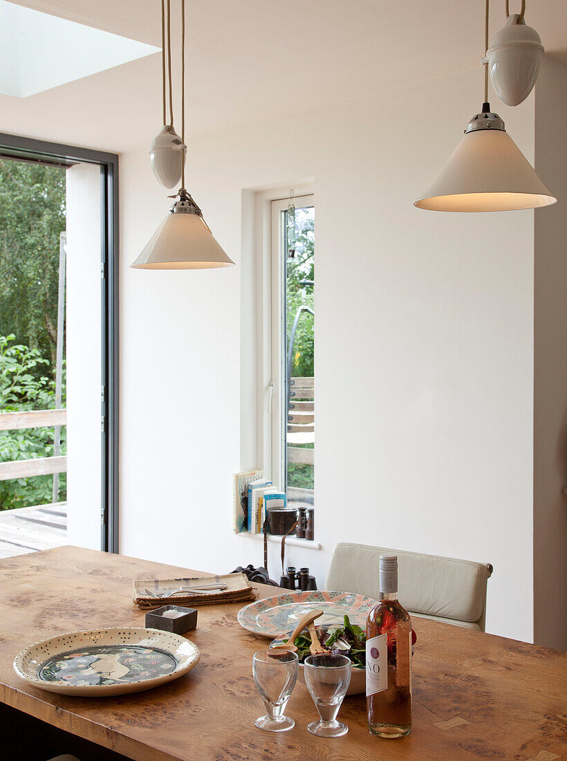 Pendant lights above dining table with plates for lunch in Essex home UK