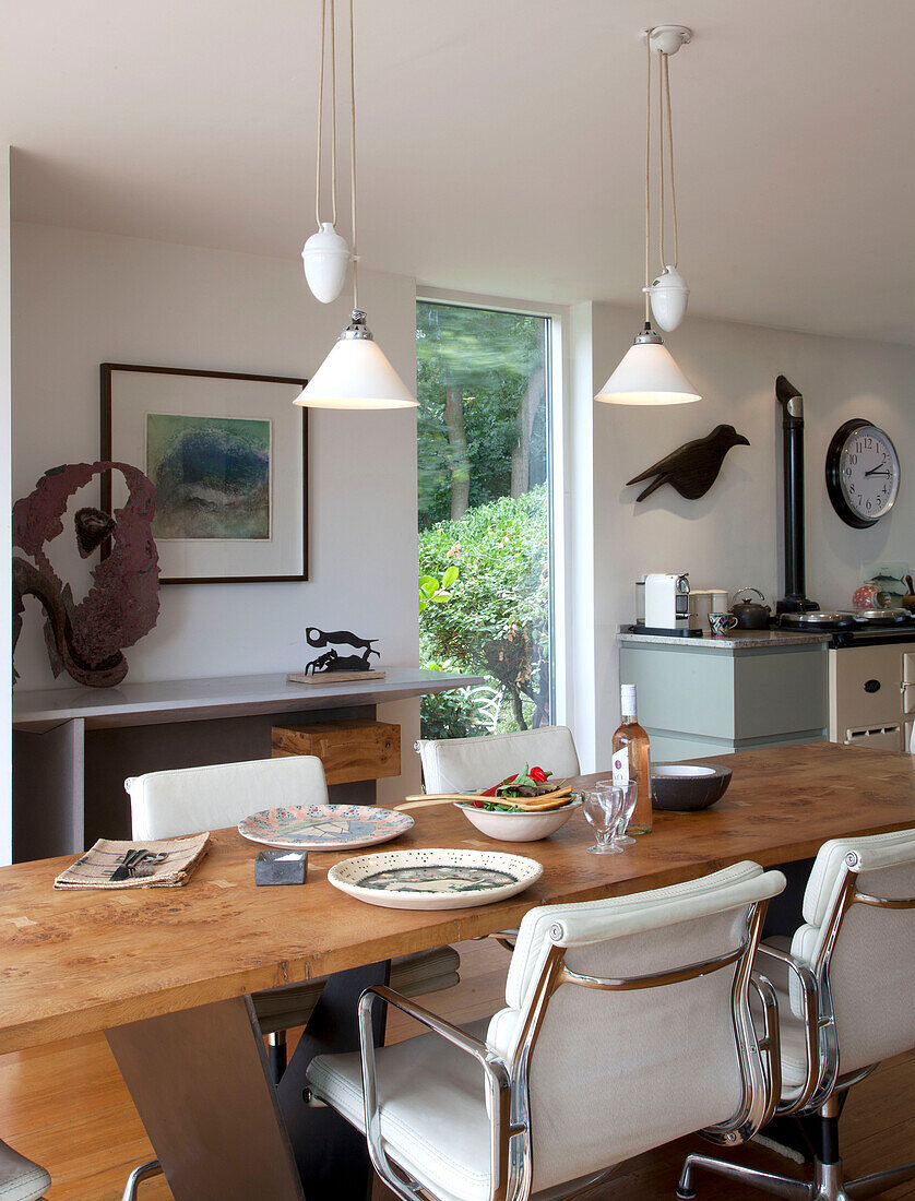 White leather chairs with pendant lights above dining table in Essex home UK