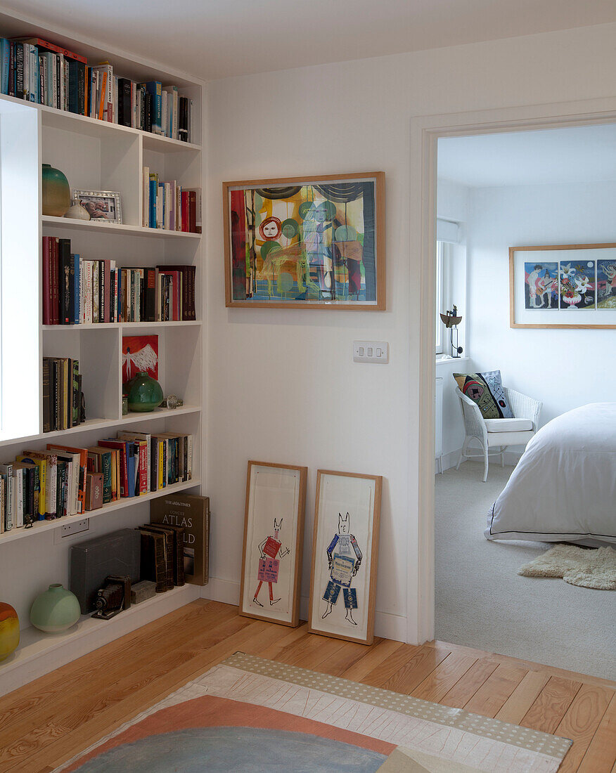 Bookshelf and framed art in hallway to bedroom in Essex home UK