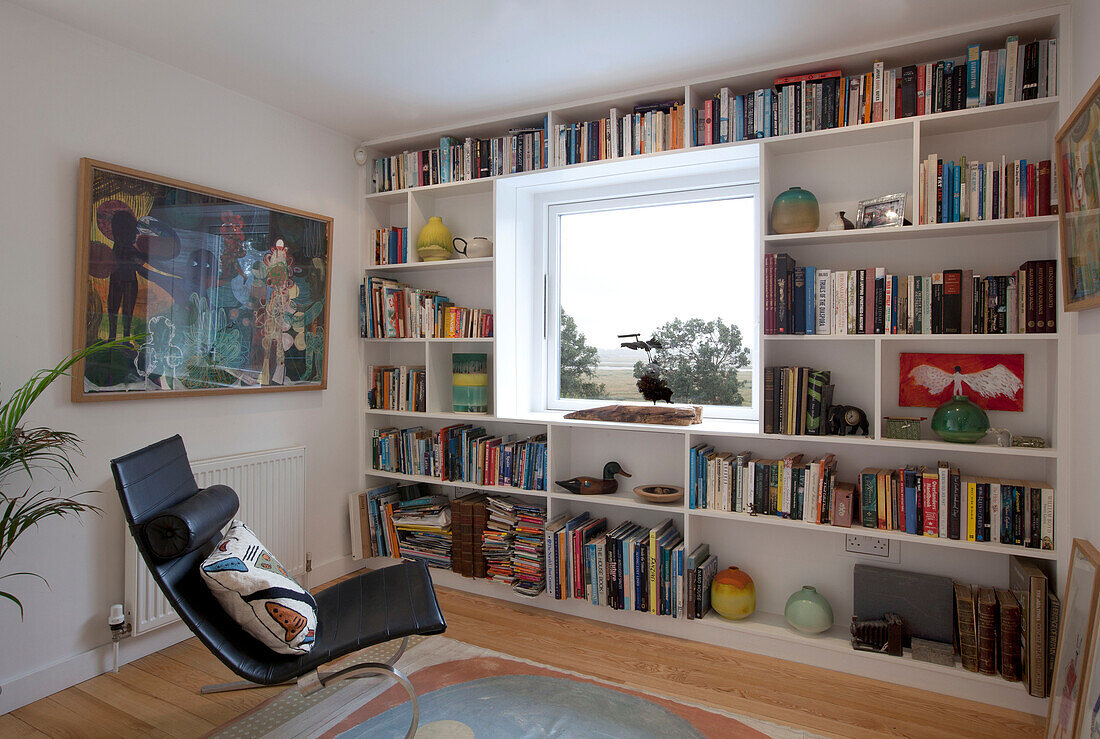 Schwarzer Sessel und gerahmte Kunst mit Bücherregal am Fenster im Schlafzimmer in Essex UK