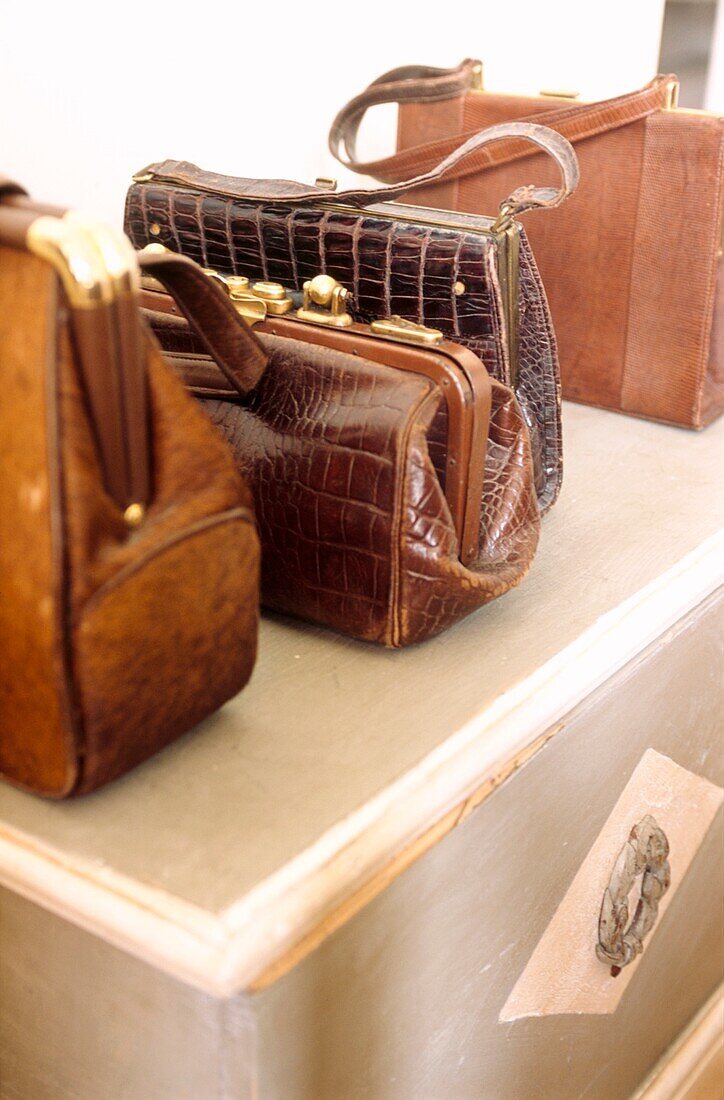 Collection of vintage leather handbags on painted wooden chest 