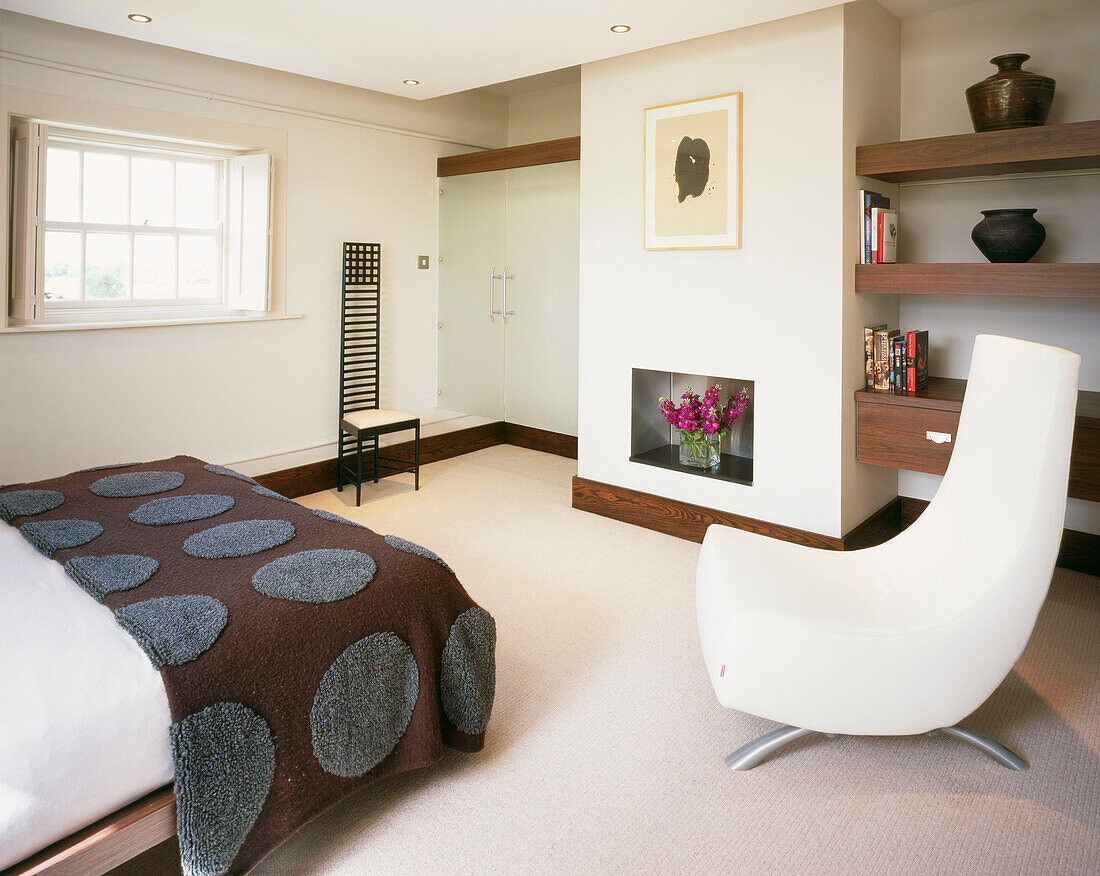 Modernes Hauptschlafzimmer mit gepolstertem weißen Stuhl