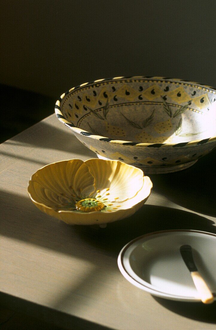 Still life of decorative ceramic bowls and plate with knife