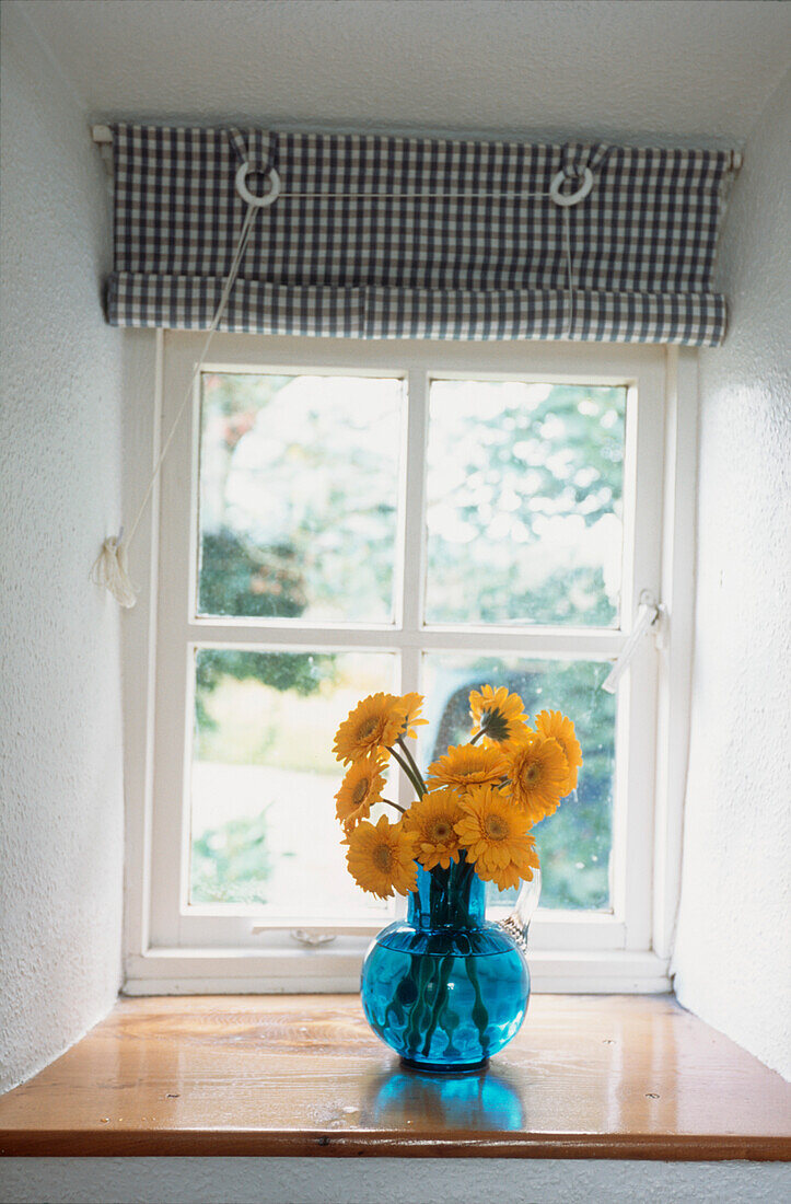 Gelbe Gerbera-Blumen auf der Fensterbank in einem Schlafzimmer
