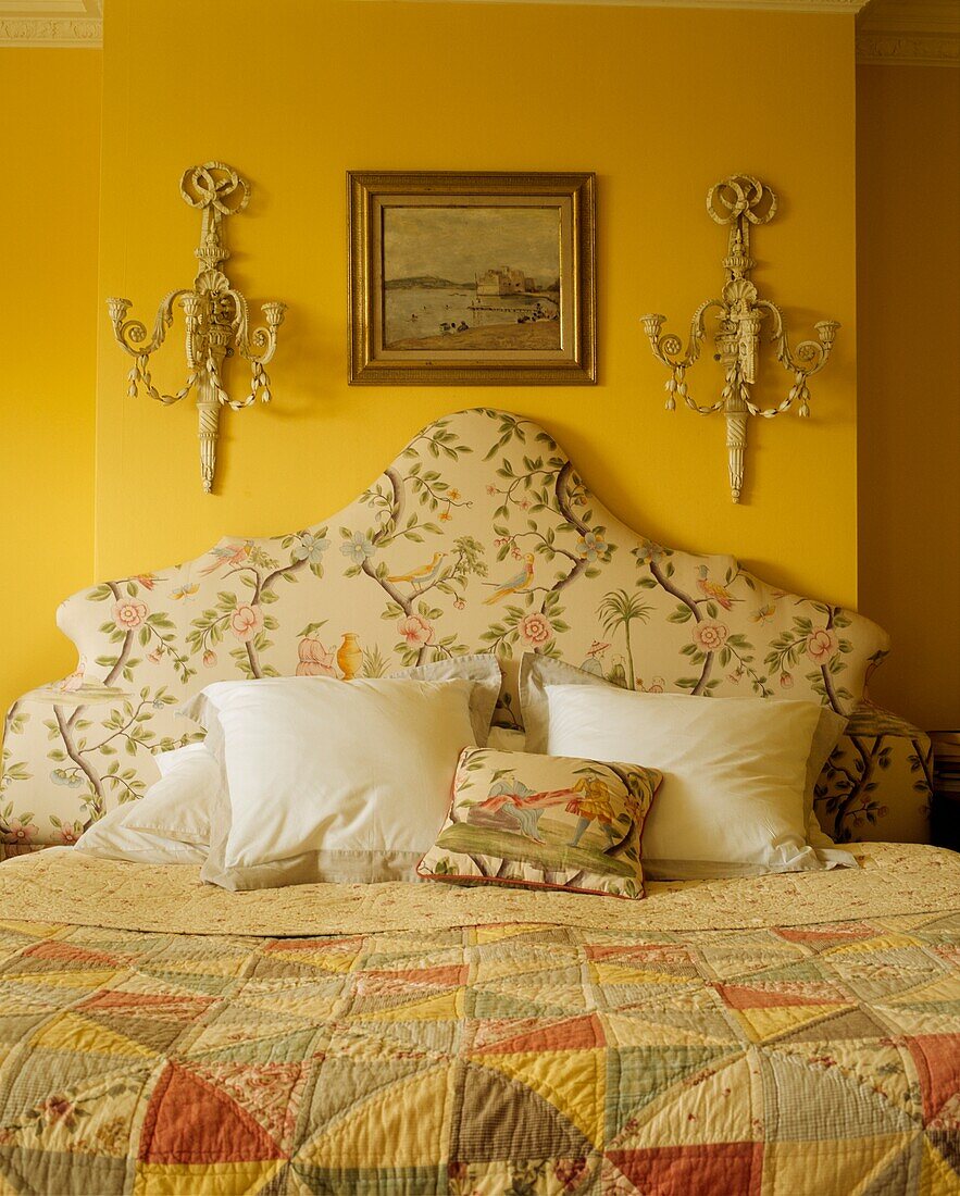 Detail eines Doppelbetts in einem dekorativen gelben Schlafzimmer