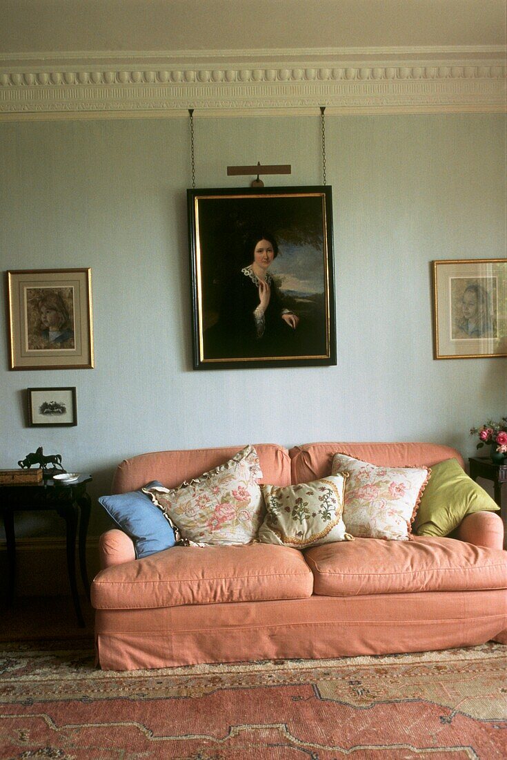 Pink upholstered sofa with portrait painting in sitting room