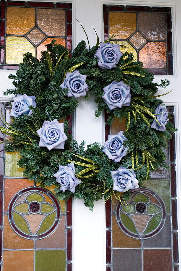 Christmas flowers on wreath in stained glass front door
