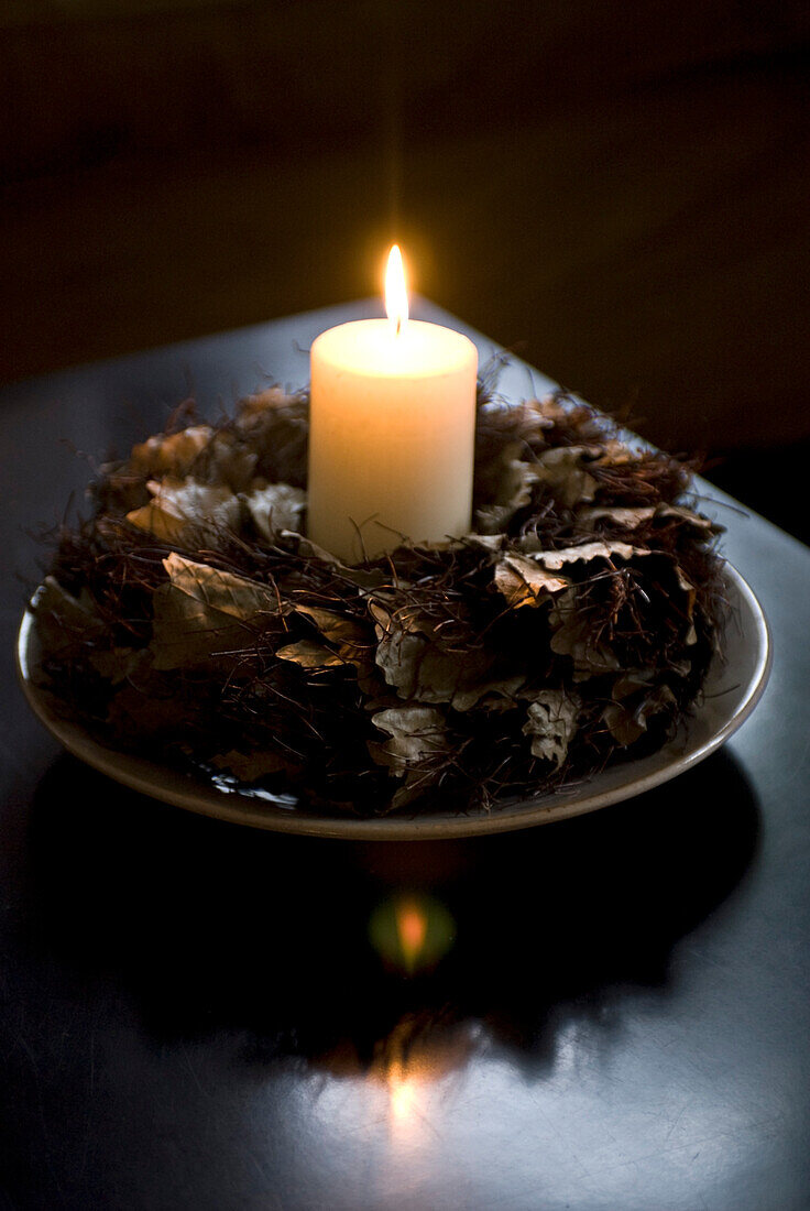 Lit candle with wreath of leaves