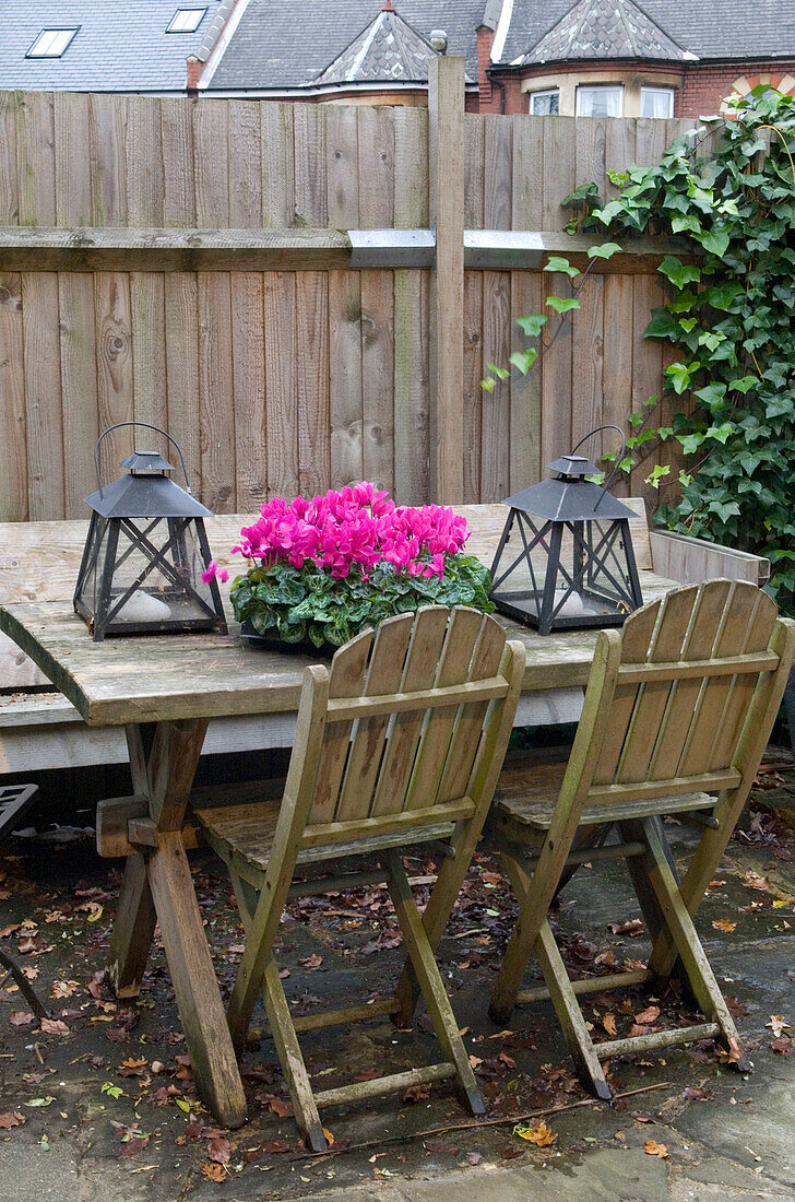 Umzäunter Tisch und Stühle mit rosa Blumen und Laternen