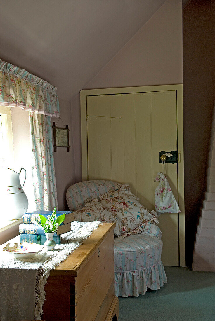 Floral cushions on chair in corner of cottage bedroom