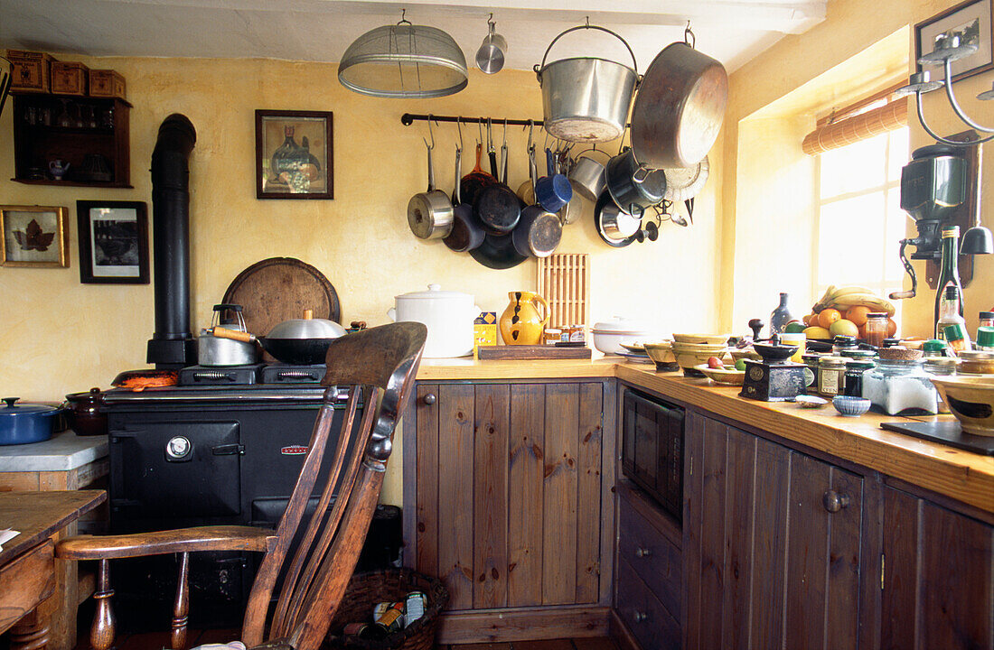 Wooden tongue and groove kitchen units painted in wood stain with a Windsor chair 