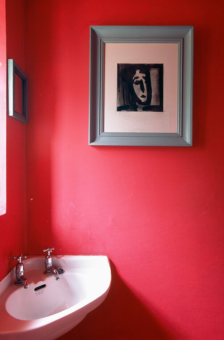 Corner washbasin in vibrant pink cloakroom with modern artwork