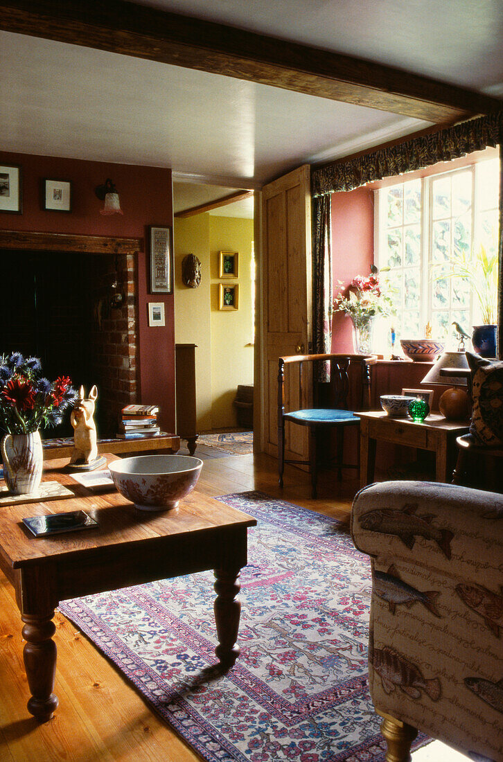 Holztisch und gemusterter Teppich in einer gemütlichen Wohnung mit offenem Ziegelsteinkamin