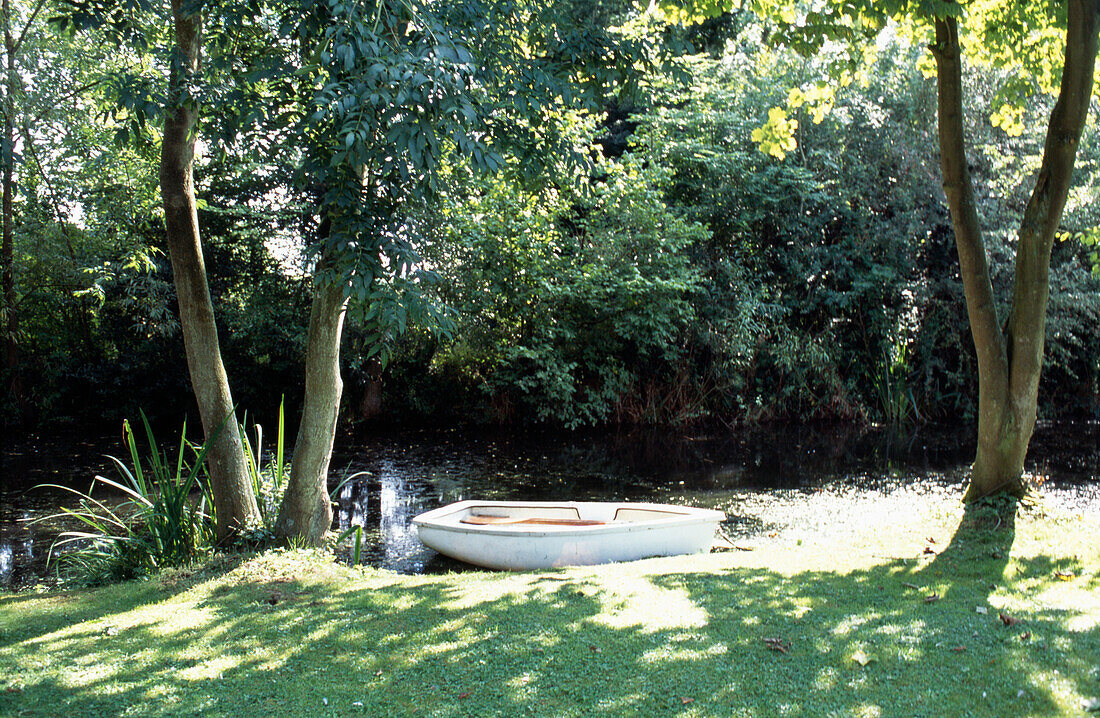 Rowing boat moored on riverbank in Suffolk garden