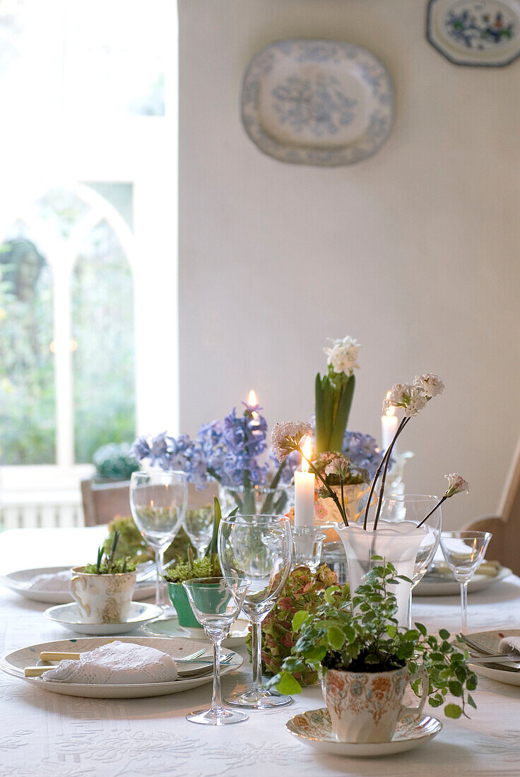 Hübsch gedeckter Tisch mit Kerzen, Hyazinthen und Zwiebeln als Tischdekoration