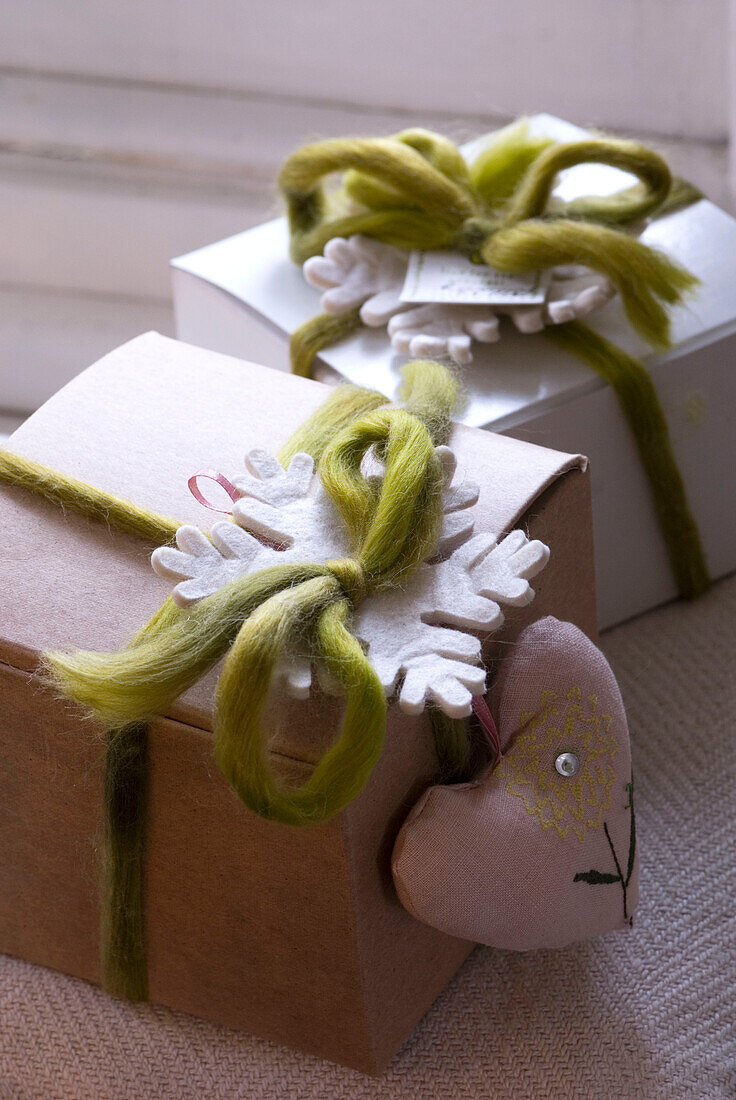 Mit Stoff bezogene Geschenkschachteln mit grünem Wollband verschnürt und mit einer Schneeflocke aus Filz und einer herzförmigen Lavendeltasche aus Stoff verziert