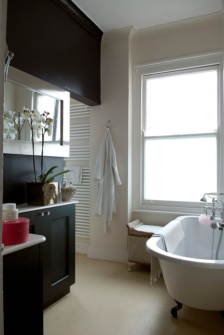 Unverkleidetes Sprossenfenster im Badezimmer mit schwarzen Beschlägen und freistehender Badewanne
