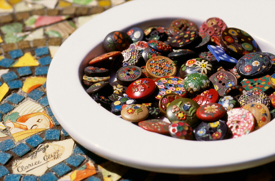 Eine Schale mit dekorierten Knöpfen auf einer Mosaik-Tischplatte