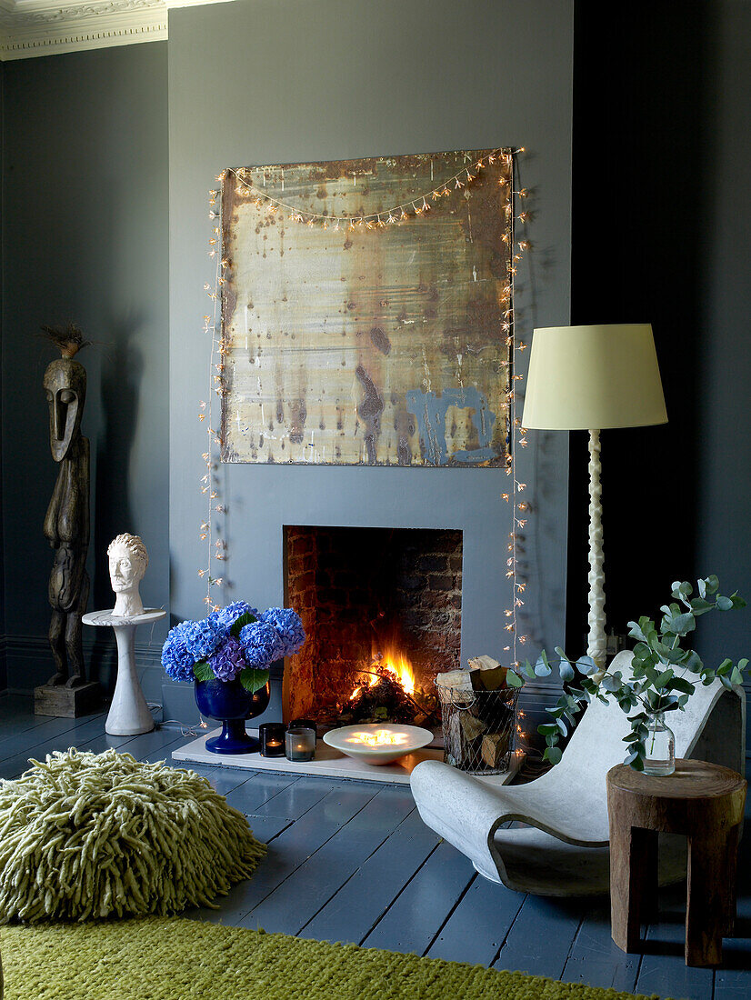 In Grautönen dekoriertes Wohnzimmer mit offenem Kamin und weihnachtlichen Lichtern und Kerzen