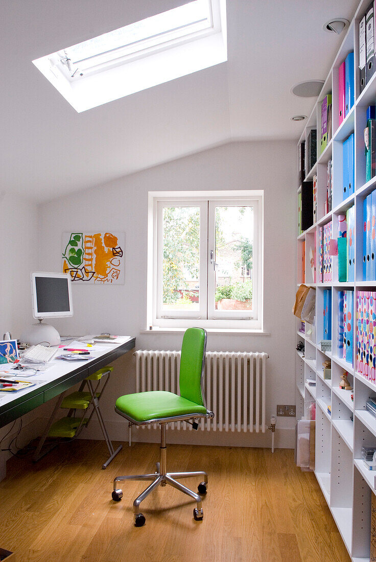 Weißes Arbeitszimmer mit Schreibtisch, Bücherregal und lindgrünem Stuhl