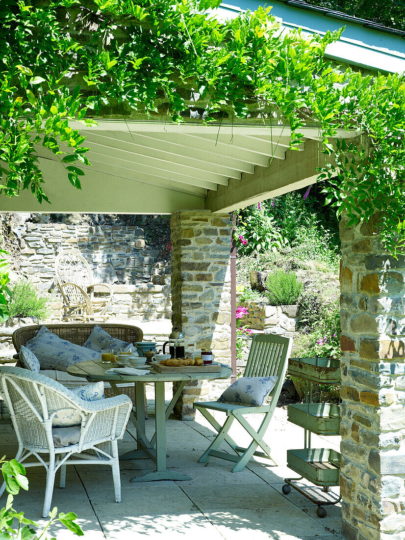 Breakfast on table of shaded garden terrace