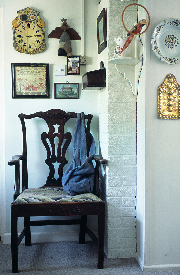 Handtasche auf antikem Stuhl mit Kunstwerk in einem weiß getünchten Hausflur