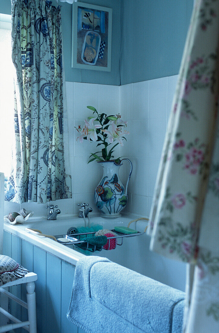 Lily on vase on corner of bath tub with rack