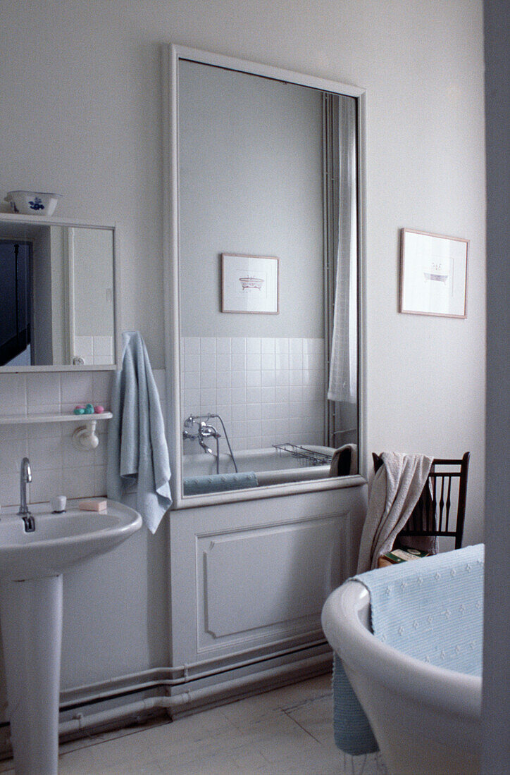 Large mirror and reflection with light blue towels in French bathroom