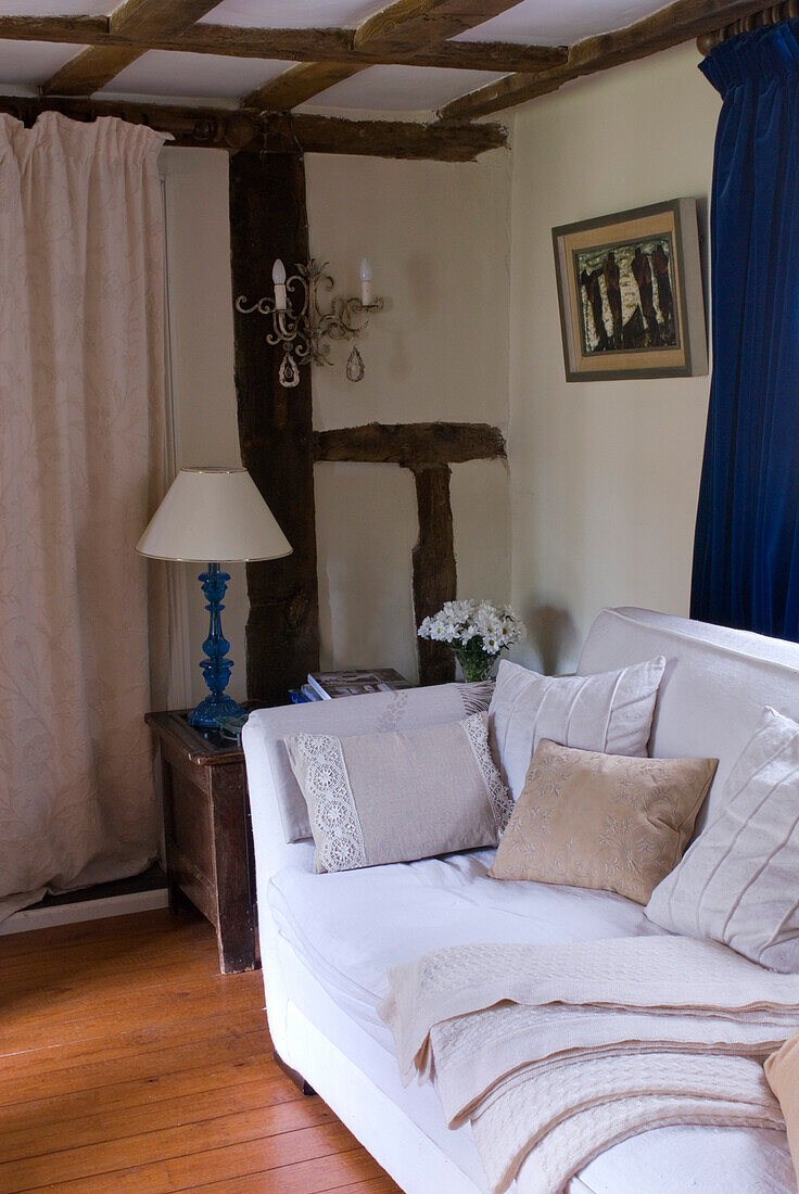 Cremefarbenes Sofa mit Kissen und Decken in einem Landhaus