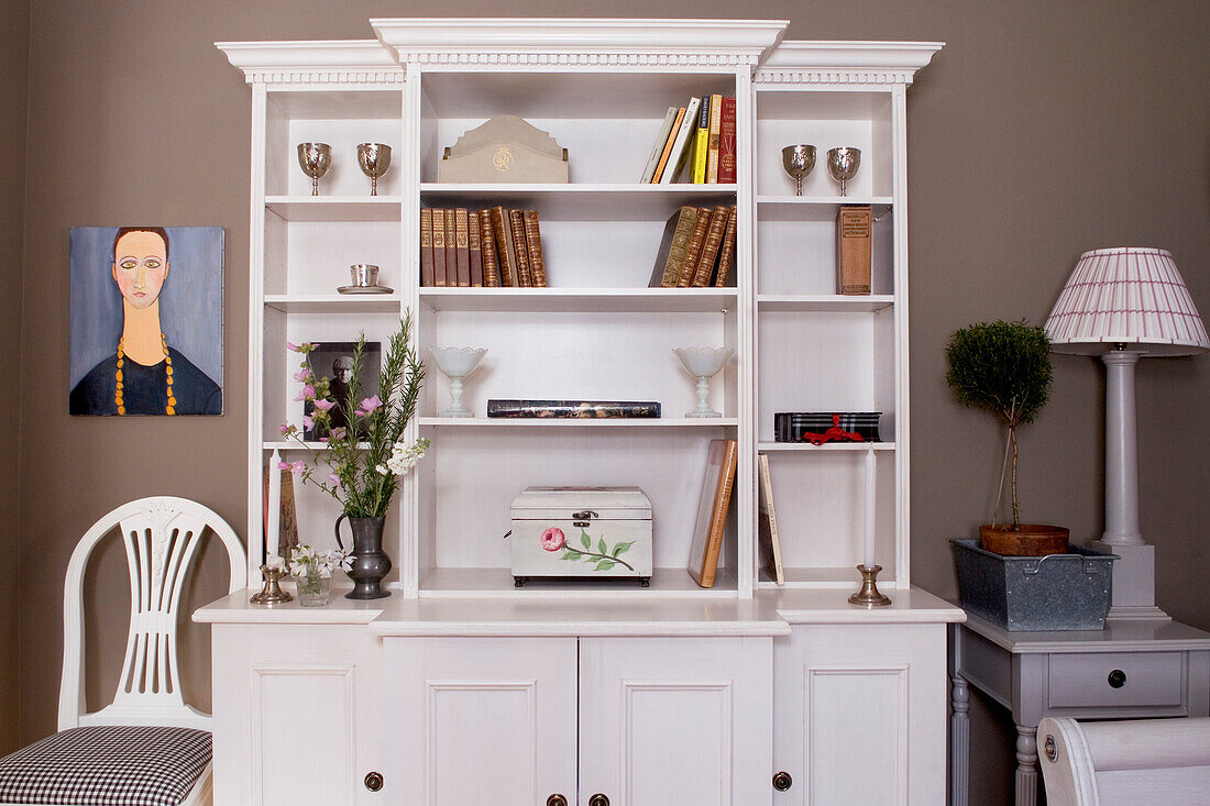 Beakfront bookcase and portrait over chair upholstered in gingham