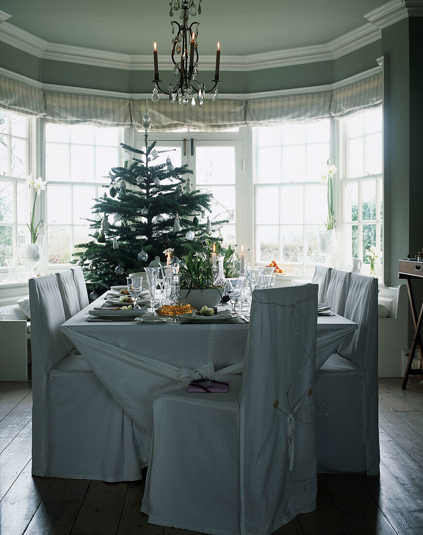Esstisch mit Gedecken und Weihnachtsbaum dahinter