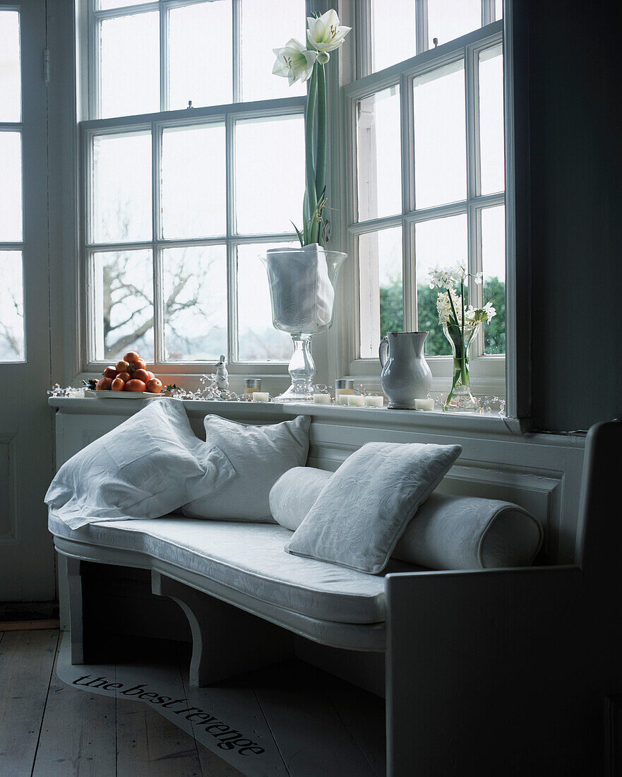 Weiße Holzbank mit Kissen neben dem Fenster im Esszimmer