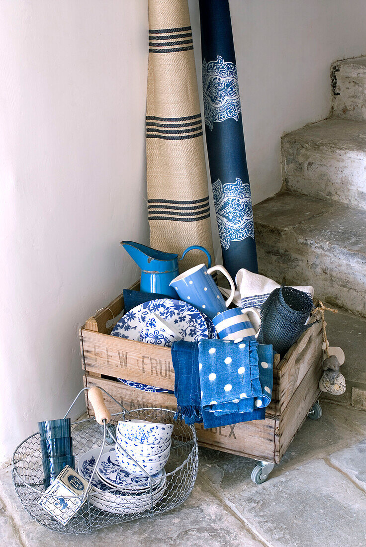 Kiste voll mit blauem Geschirr und Textilien