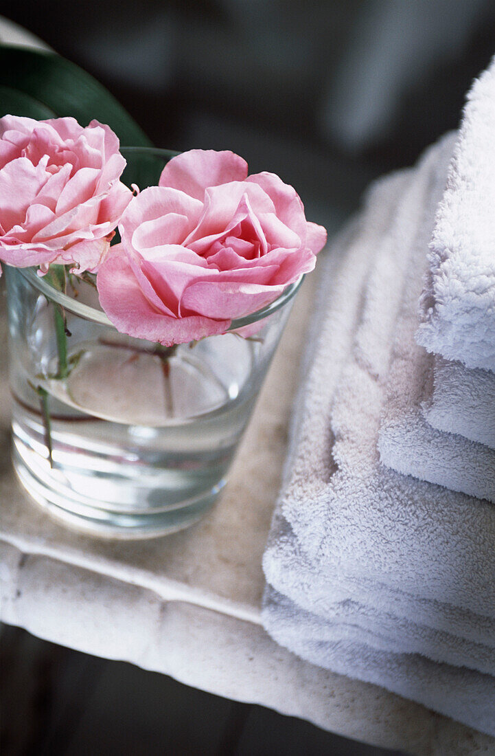 Pink roses in glass by towels
