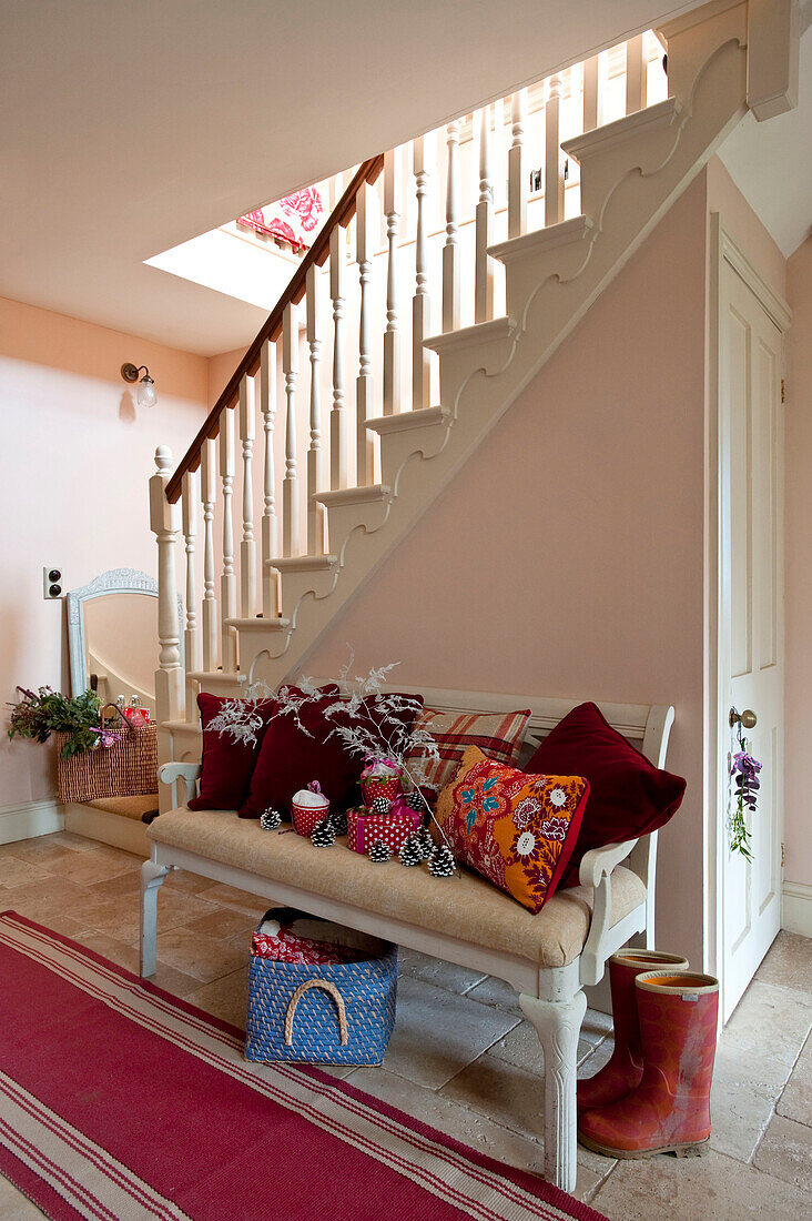 Wellington boots and Christmas cushions on bench seat in country house hallway