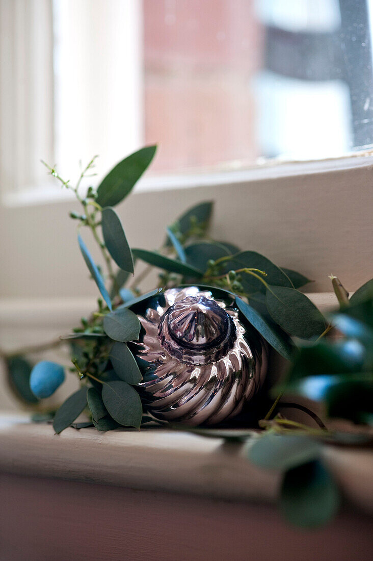Leaf decoration and metallic bauble on windowsill of country home