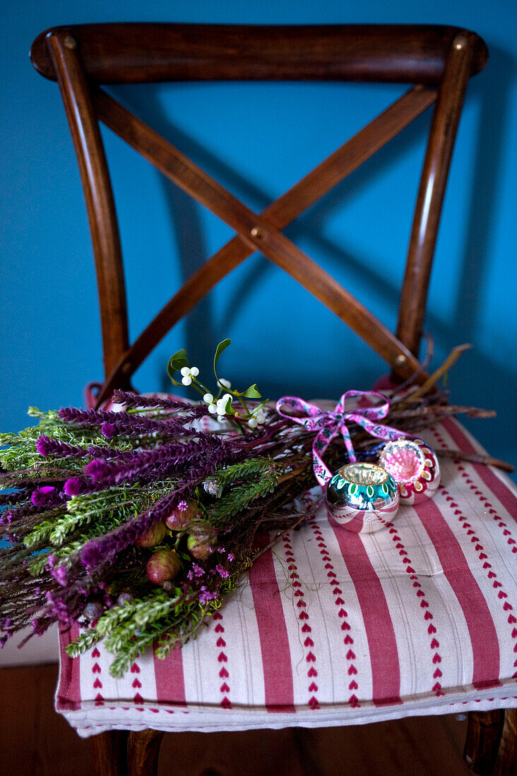 Posy of flowers with Christmas baubles on patterned wood chair